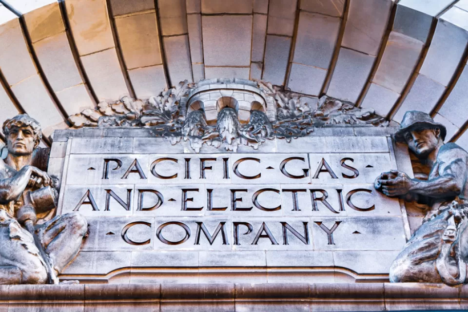 Close-up of Pacific Gas & Electric Company title carved into building facade, flanked by two statues of utility workers